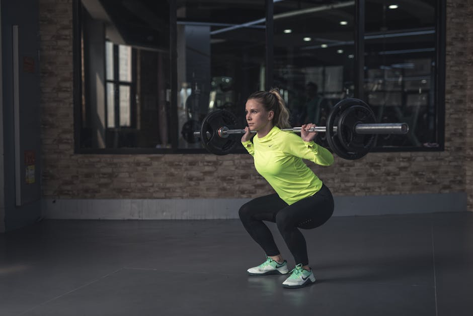 Dedicated woman in neon activewear performs a weighted squat in an indoor gym setting